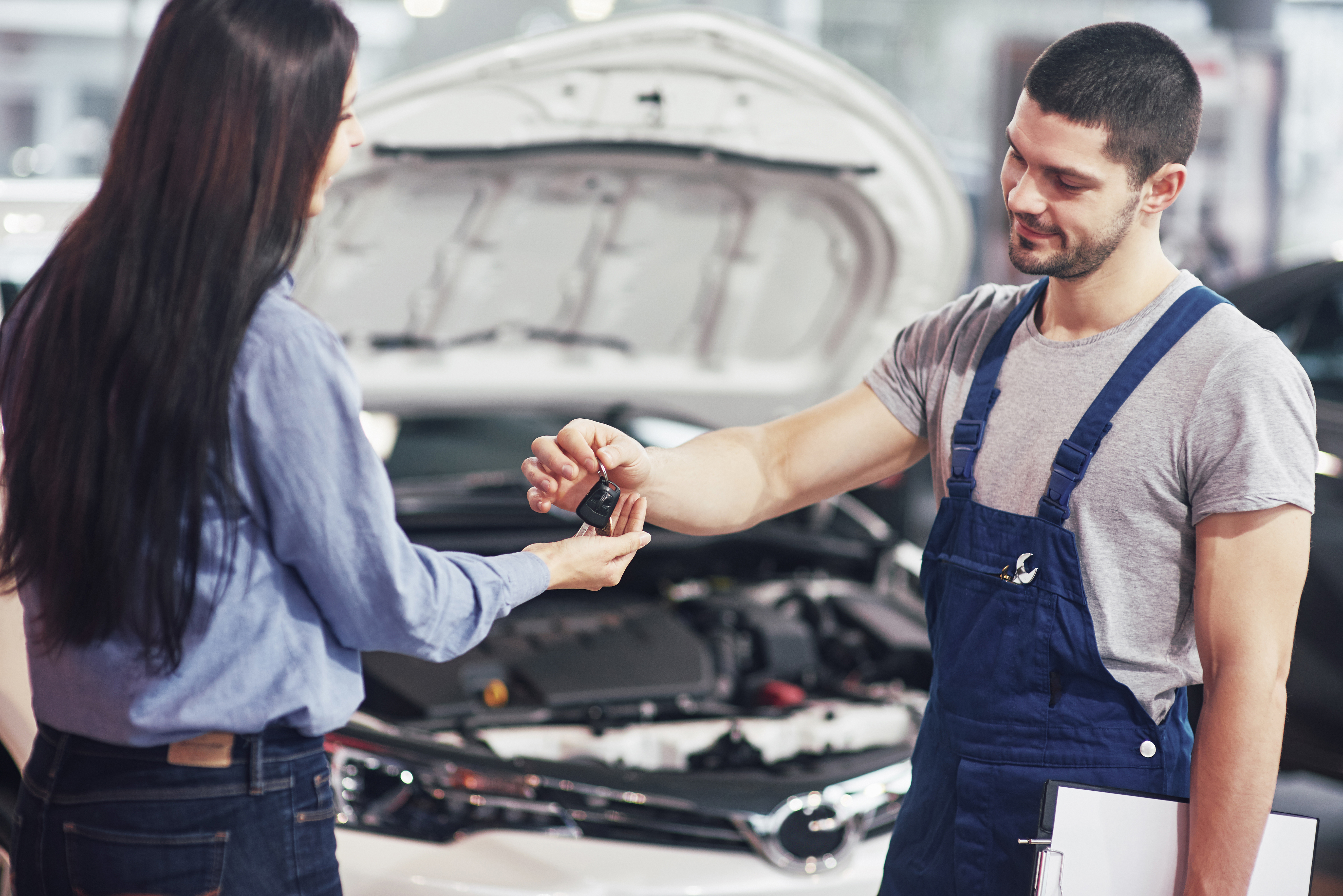 cropped view of mechanic giving car keys to female client.